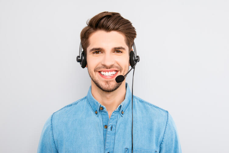 Bild vergrößern: handsome young man in work in  call-centre with headphones and s