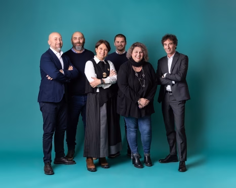 Group of five in suits on teal backdrop - GETEC